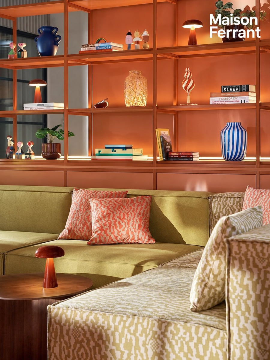 Un salon chaleureux avec un canapé, des coussins et une bibliothèque orange